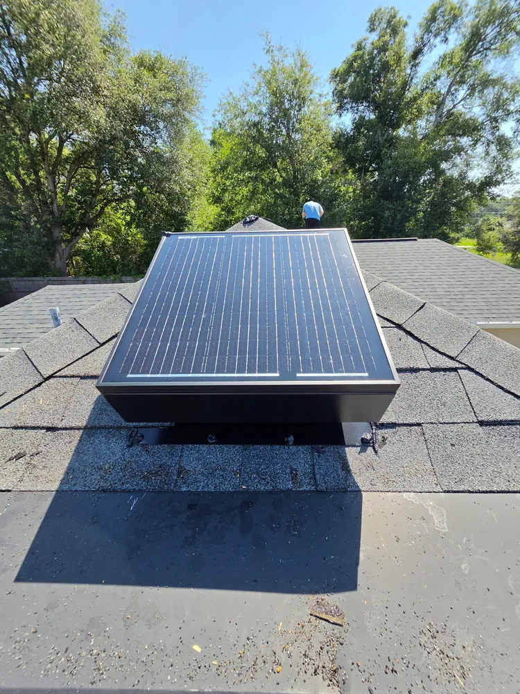 Completed solar attic fan installation on a grey shingle roof